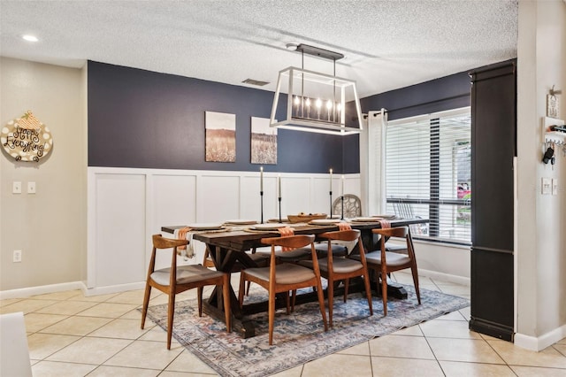 tiled dining room with a textured ceiling and an inviting chandelier