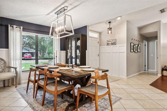 dining room with a healthy amount of sunlight, a textured ceiling, light tile patterned flooring, and a chandelier