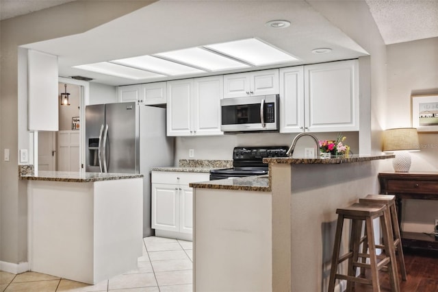 kitchen with black / electric stove, white cabinetry, dark stone counters, and kitchen peninsula