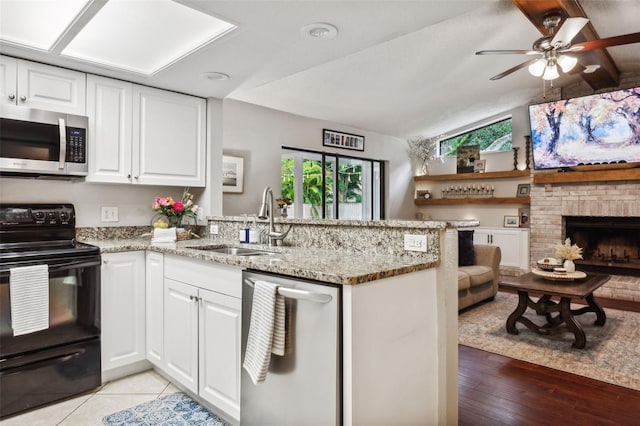 kitchen featuring lofted ceiling, kitchen peninsula, appliances with stainless steel finishes, and white cabinetry