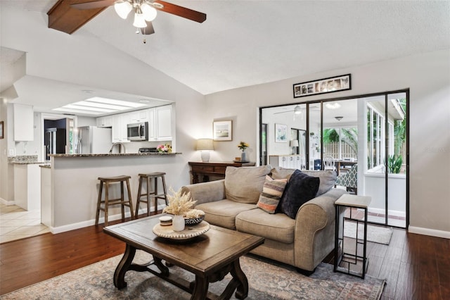 living room with ceiling fan, vaulted ceiling, and wood-type flooring