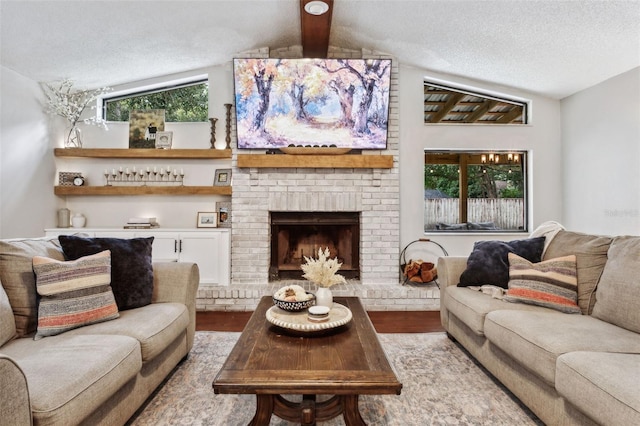 living room with a textured ceiling, light hardwood / wood-style floors, a brick fireplace, and lofted ceiling with beams