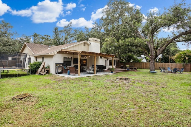 back of property with a lawn, a patio, and a trampoline