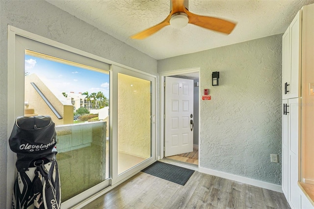 entryway featuring light wood-type flooring, ceiling fan, and a textured ceiling