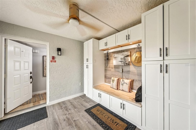 mudroom with a textured ceiling and light hardwood / wood-style floors