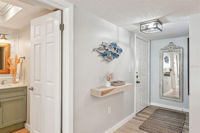 entryway featuring light wood-type flooring, sink, and a textured ceiling