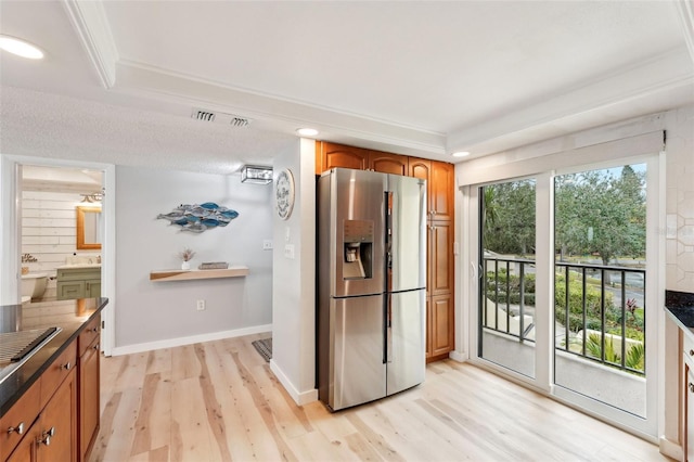 kitchen featuring a raised ceiling, stainless steel refrigerator with ice dispenser, sink, crown molding, and light hardwood / wood-style flooring