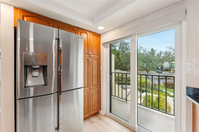 kitchen featuring light wood-type flooring, ornamental molding, stainless steel fridge, and dark stone counters