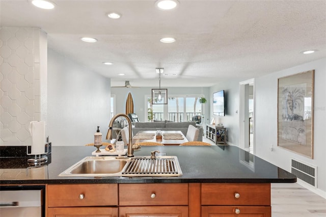 kitchen with a textured ceiling, dishwasher, light hardwood / wood-style flooring, and sink