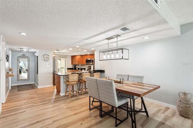 dining room with a textured ceiling and light hardwood / wood-style floors