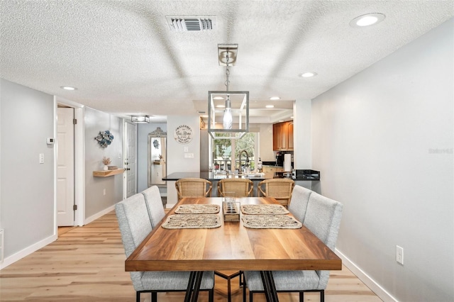 dining room featuring a textured ceiling and light hardwood / wood-style flooring