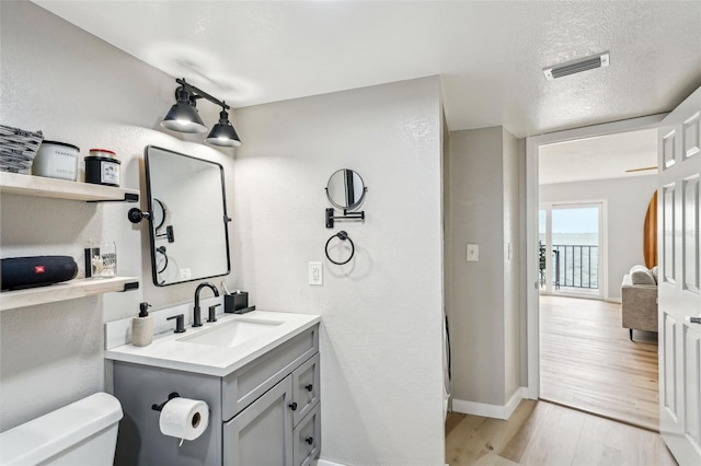 bathroom with toilet, vanity, a textured ceiling, and hardwood / wood-style floors