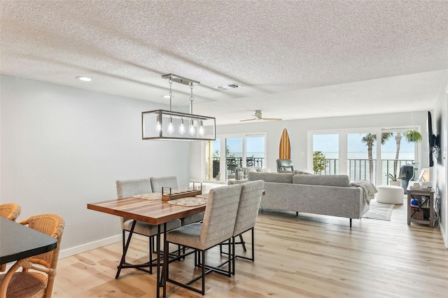 dining room with ceiling fan, a textured ceiling, a wealth of natural light, and light wood-type flooring