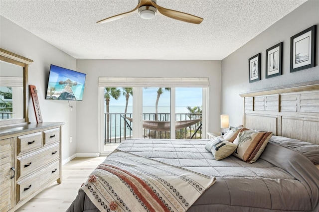 bedroom featuring ceiling fan, access to exterior, a textured ceiling, and light wood-type flooring