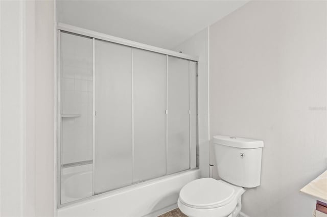 bathroom featuring toilet and bath / shower combo with glass door