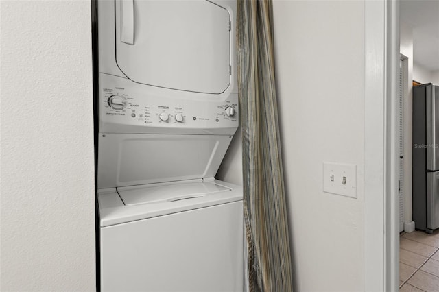 laundry room featuring light tile patterned floors and stacked washer / drying machine