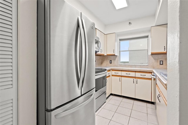 kitchen featuring backsplash, white cabinetry, light tile patterned floors, and appliances with stainless steel finishes