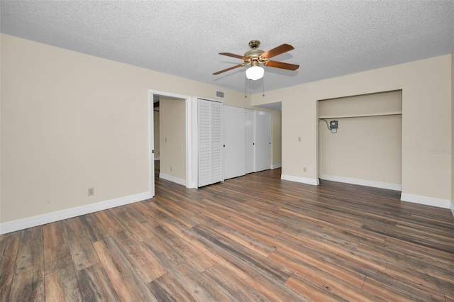 unfurnished bedroom featuring ceiling fan, two closets, a textured ceiling, and dark hardwood / wood-style flooring