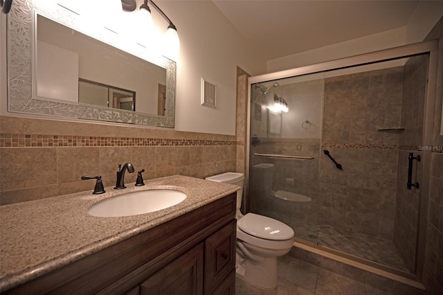 bathroom featuring vanity, a shower with door, tile walls, and toilet