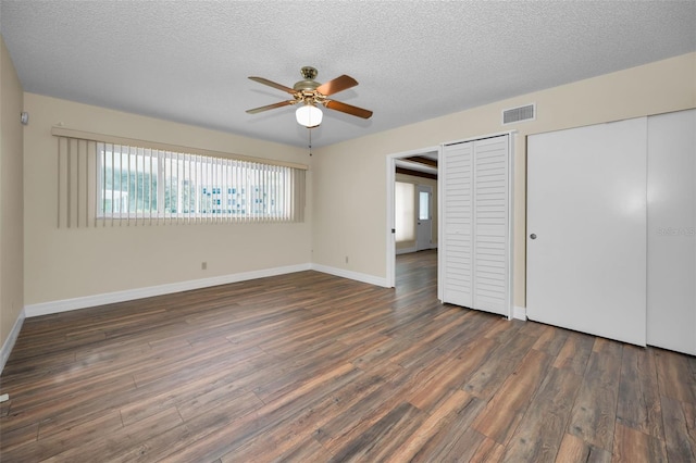 unfurnished bedroom featuring dark wood-type flooring, a closet, ceiling fan, and a textured ceiling