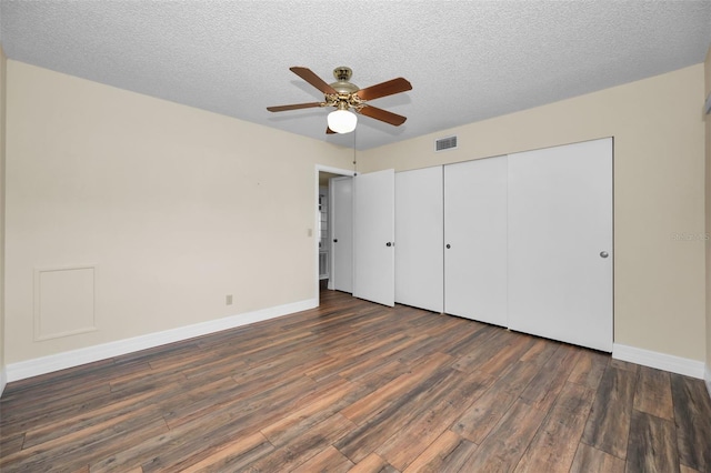 unfurnished bedroom with ceiling fan, dark wood-type flooring, a textured ceiling, and a closet