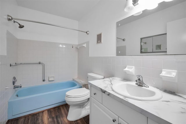 full bathroom with tile walls, tiled shower / bath combo, vanity, wood-type flooring, and toilet