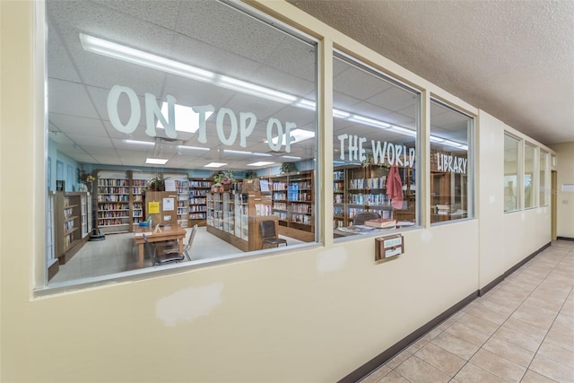 interior space with light tile patterned flooring and a drop ceiling