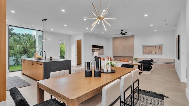 dining space with ceiling fan with notable chandelier and sink