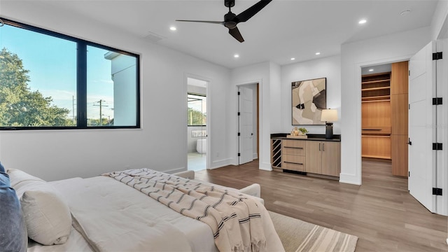 bedroom with ceiling fan, a spacious closet, light hardwood / wood-style floors, and ensuite bath