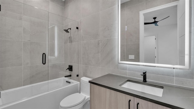 full bathroom featuring toilet, tiled shower / bath combo, tile walls, and vanity