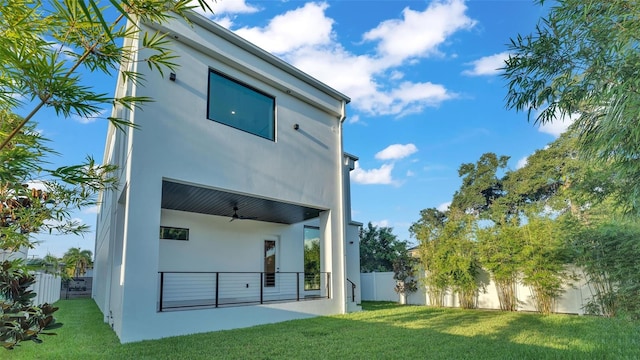 back of property featuring a lawn, ceiling fan, and a patio