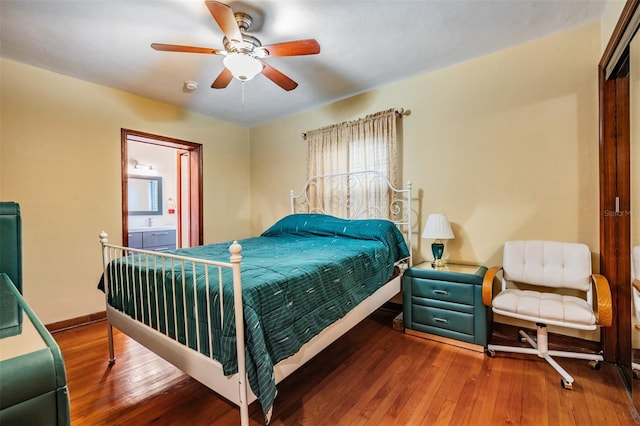 bedroom with ceiling fan, ensuite bath, multiple windows, and hardwood / wood-style floors