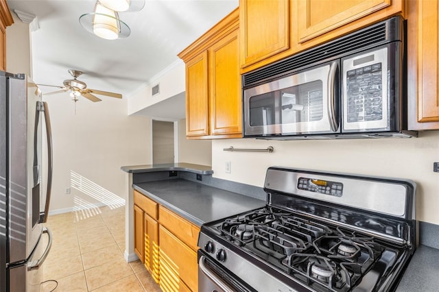 kitchen with light tile patterned flooring, ceiling fan, appliances with stainless steel finishes, and ornamental molding