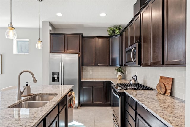 kitchen with stainless steel appliances, light stone countertops, decorative backsplash, sink, and dark brown cabinets