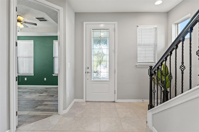 tiled foyer entrance with a textured ceiling and ceiling fan