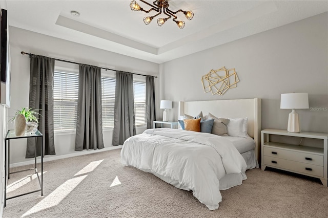 carpeted bedroom with a raised ceiling and a chandelier