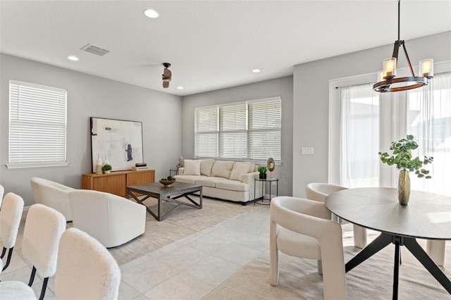 living room featuring an inviting chandelier, light tile patterned floors, and a wealth of natural light