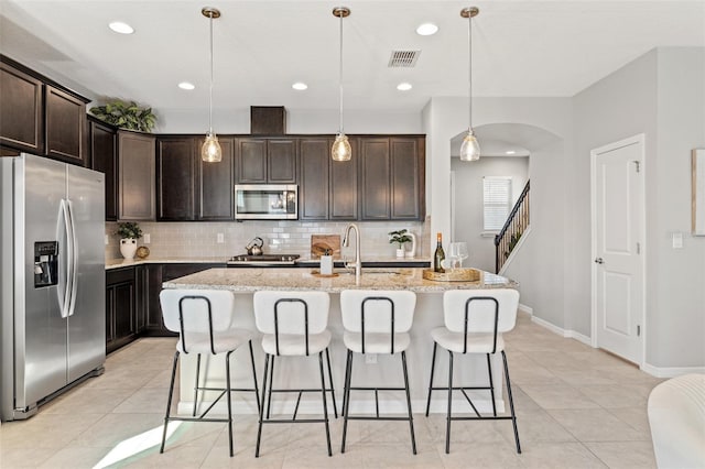 kitchen featuring sink, decorative light fixtures, decorative backsplash, a kitchen island with sink, and appliances with stainless steel finishes