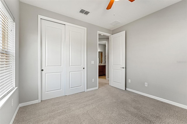 unfurnished bedroom featuring ceiling fan, a closet, and light carpet