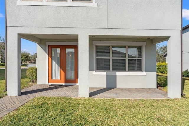 doorway to property featuring a lawn and a patio