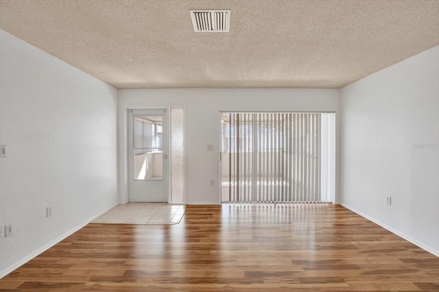 empty room with a textured ceiling and light wood-type flooring