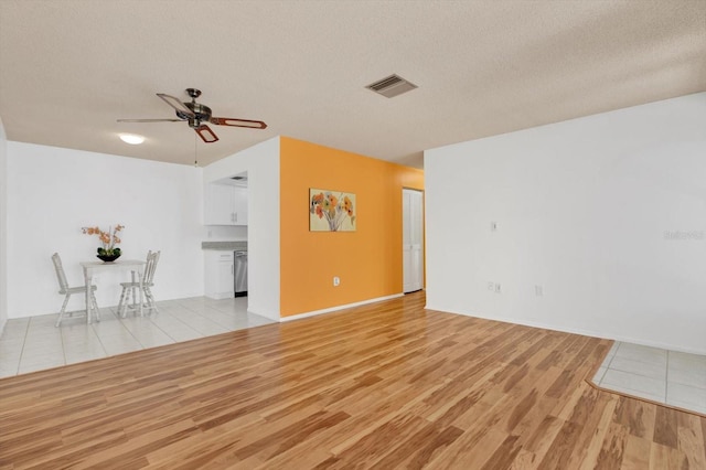 unfurnished living room featuring a textured ceiling, ceiling fan, and light hardwood / wood-style flooring