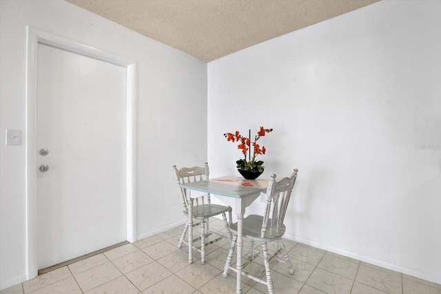 tiled dining space with a textured ceiling