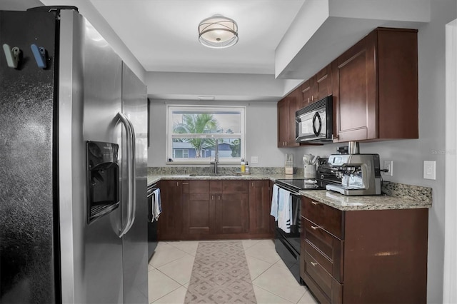 kitchen with light stone countertops, light tile patterned flooring, sink, and black appliances