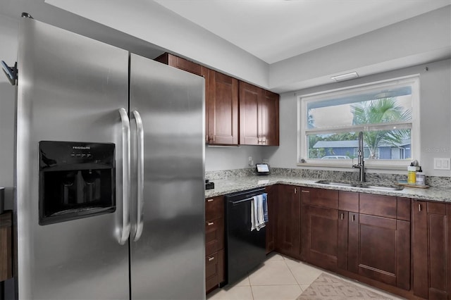 kitchen with light tile patterned floors, stainless steel refrigerator with ice dispenser, dishwasher, light stone counters, and sink