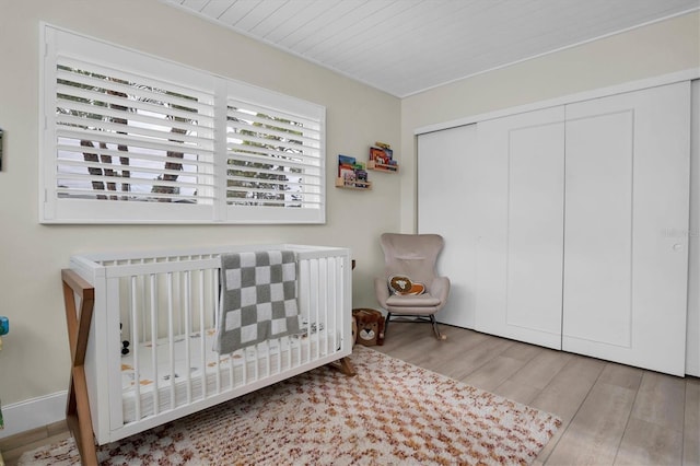 bedroom featuring light wood-type flooring, a closet, and a crib