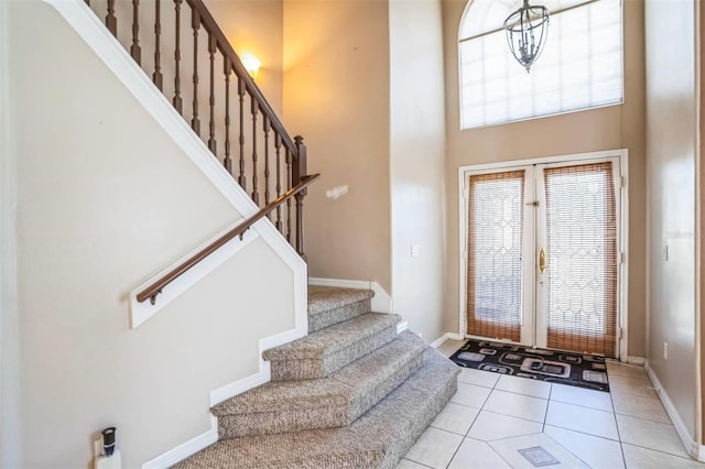 entryway with a towering ceiling and light tile patterned flooring