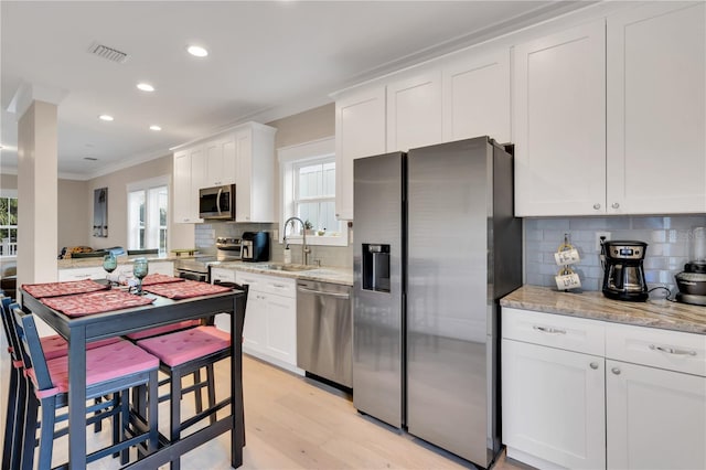 kitchen featuring sink, stainless steel appliances, light stone counters, and white cabinetry