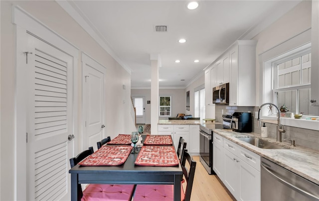 kitchen featuring white cabinets, stainless steel appliances, crown molding, and sink