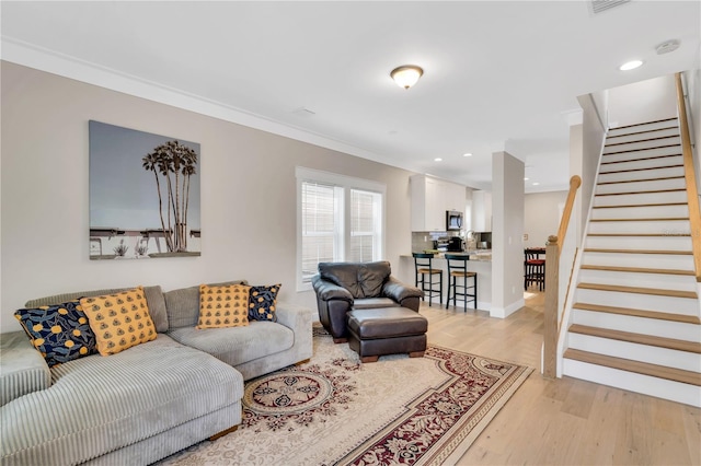 living room with light hardwood / wood-style floors and crown molding